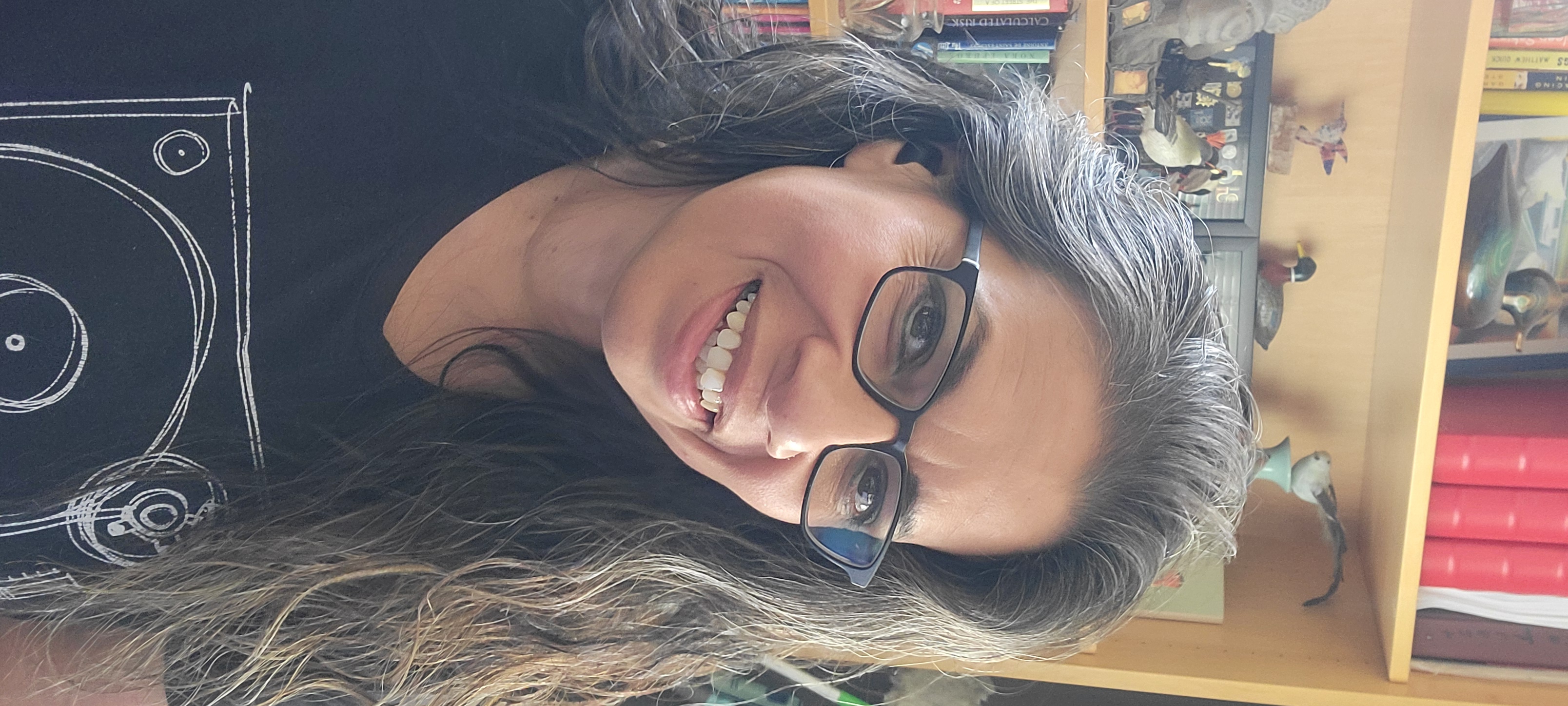 Gabriela smiling in home office with bookshelf in background